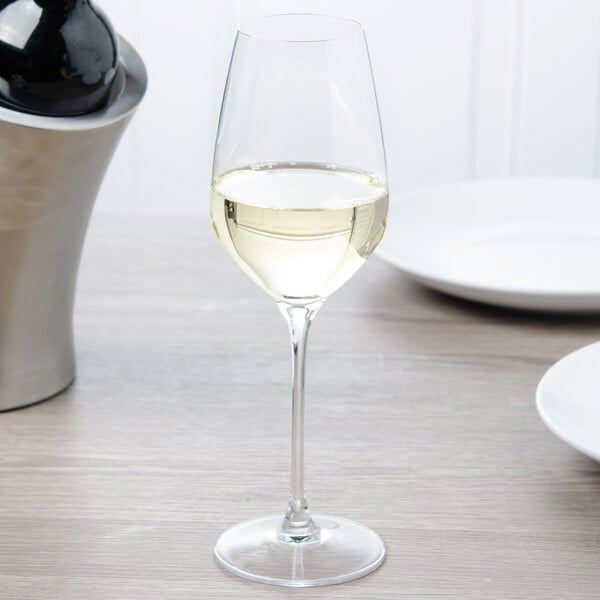 A Spiegelau white wine glass filled with white wine on a table.