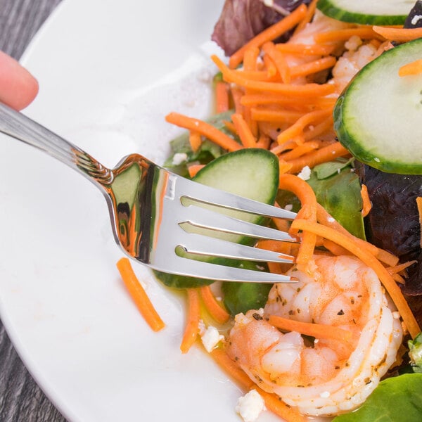 An Oneida Scroll stainless steel salad fork spearing salad with shrimp and vegetables.