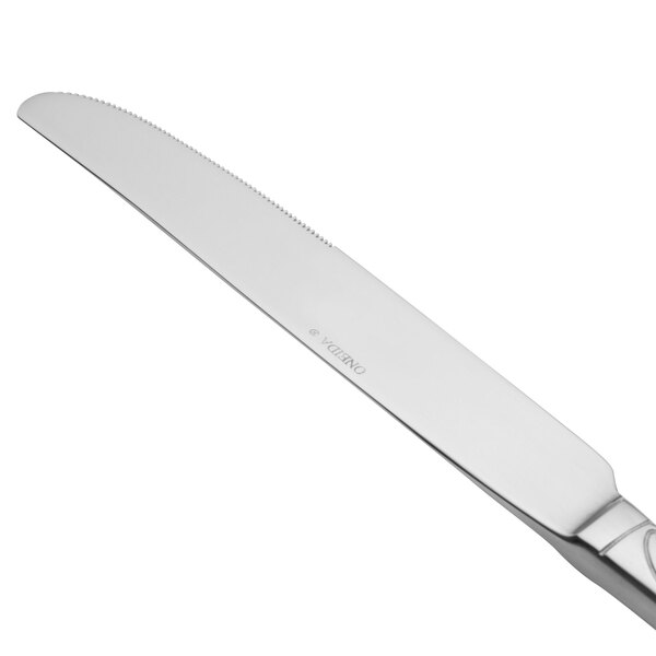 A close-up of a Oneida Scroll stainless steel dinner knife with a silver handle.