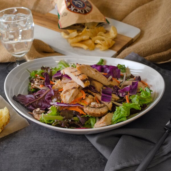 A bowl of salad with chicken and vegetables in a GET Magnolia melamine bowl.