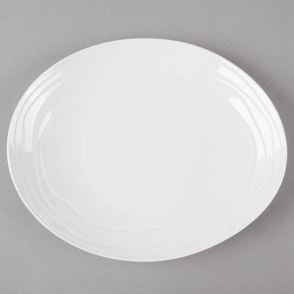 A white oval melamine platter with a textured rim on a gray surface.