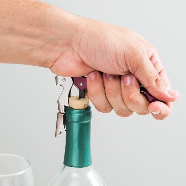 A hand using a Franmara Duo-Lever corkscrew to open a bottle of wine with a cork stopper.