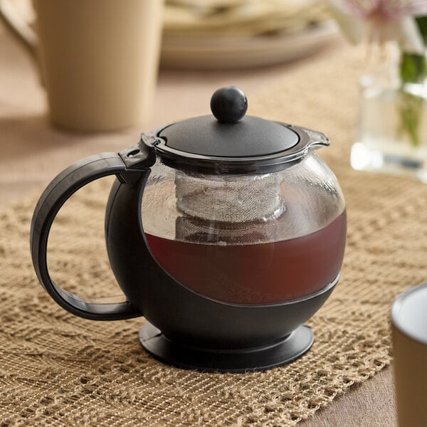 A 25 oz. tempered glass tea pot infuser with a black handle, lid, and a stainless steel basket for brewing tea.