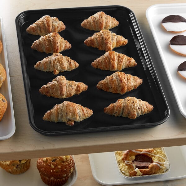 A black Cambro market tray of pastries on a bakery display counter.