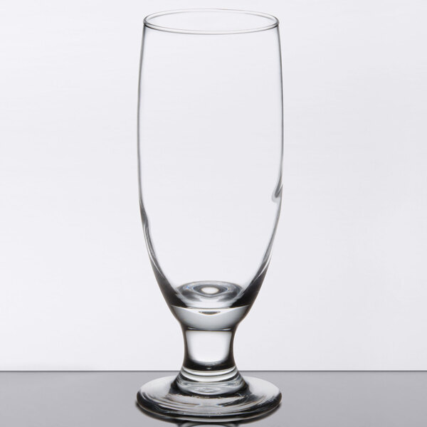 A close up of a Libbey stemmed pilsner glass with a small rim on top.