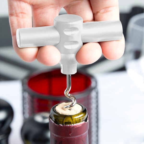 A hand using a white Franmara pocket corkscrew to open a bottle of wine.