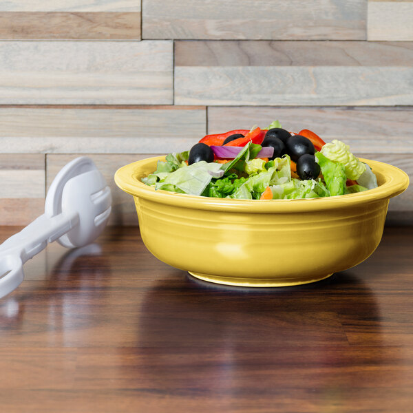 A Fiesta Sunflower china serving bowl filled with salad on a table.
