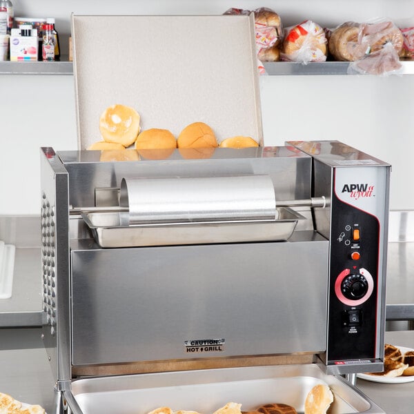 An APW Wyott vertical conveyor bun grill toaster with food inside.