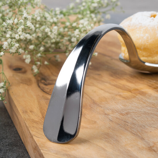 A Bon Chef stainless steel spoon on a wood surface.
