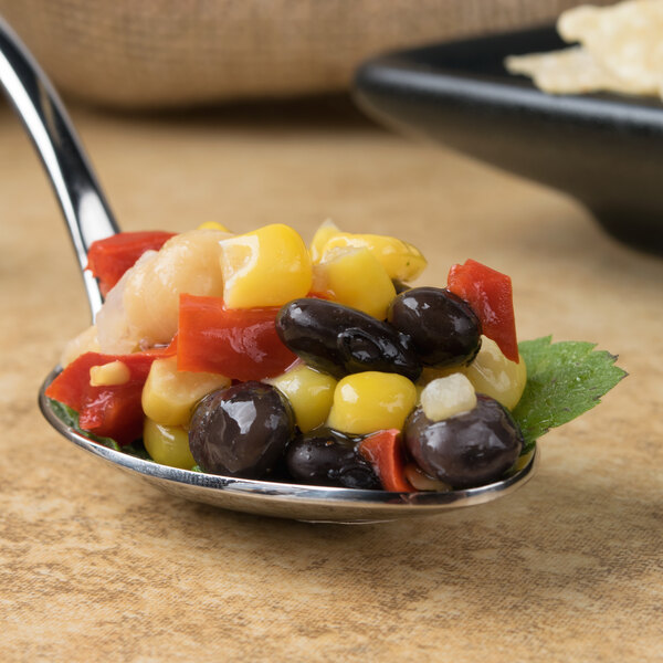 A Bon Chef stainless steel spoon filled with food on a black plate.