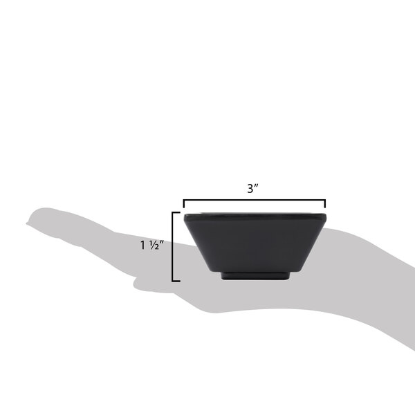 A hand holding a black square Elite Global Solutions Zen ramekin.