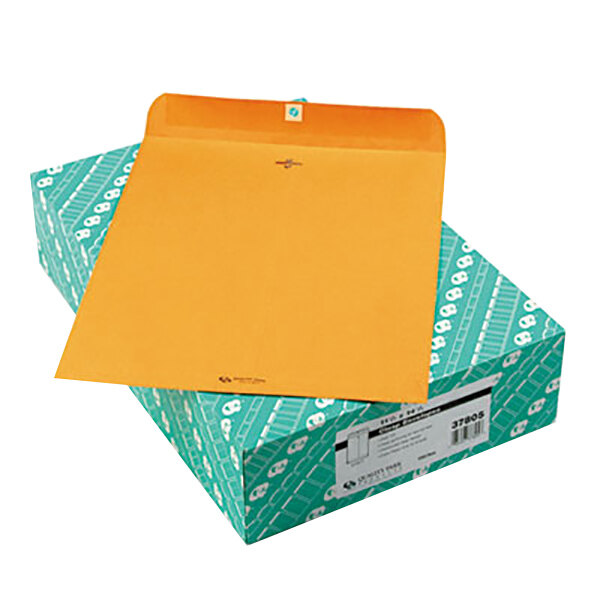 A box of Quality Park brown Kraft envelopes with an orange envelope on top.