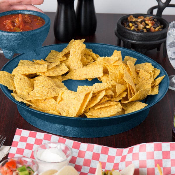 A blue bowl filled with red salsa and a bowl of chips on a table in a Mexican restaurant.