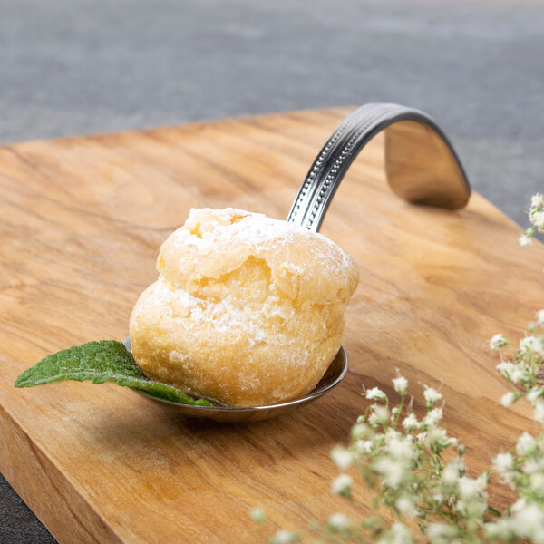 A Bon Chef stainless steel sombrero bouillon tasting spoon with food on it.