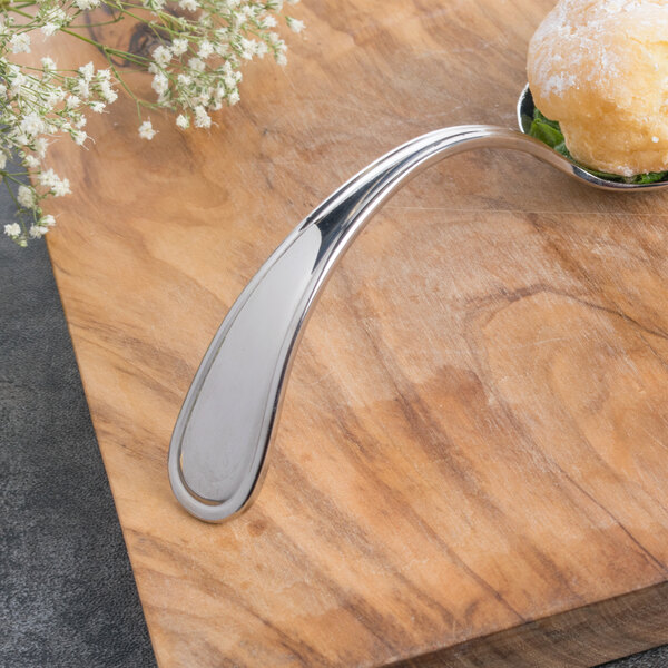A Bon Chef Tuscany bouillon tasting spoon with food on it sitting on a table.
