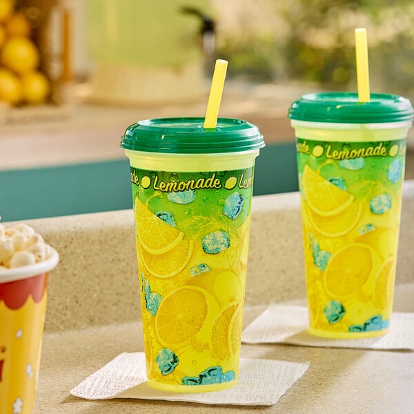 Two Clear plastic lemonade cups with lids and straws on a counter.