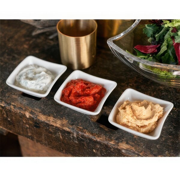 A group of white square Villeroy & Boch NewWave dip bowls filled with white and brown dips.