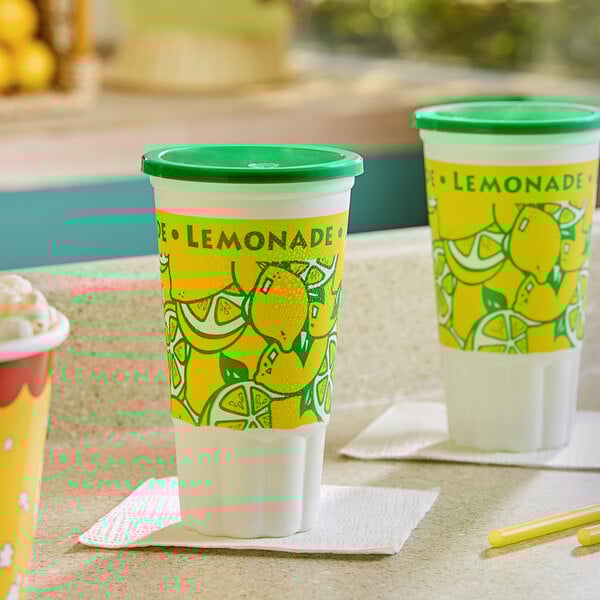 Two 32 oz. Lemonade Economy Car Cups with Green Lids on a counter.