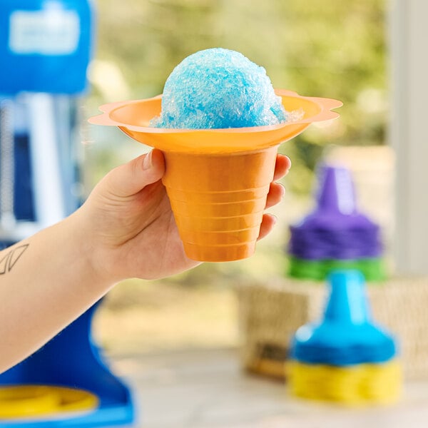 A hand holding a blue snow cone in a flower-shaped plastic cup.