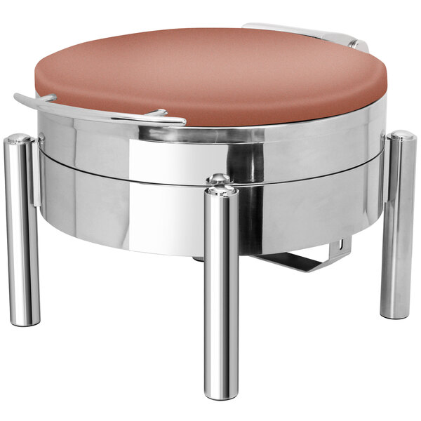 A round stainless steel chafer with a copper coating on a table in a restaurant.