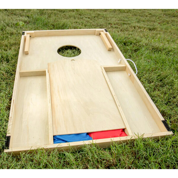 A Triumph outdoor cornhole board on grass.