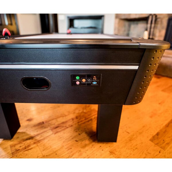 An Atomic air hockey table with black and white details and a black button.