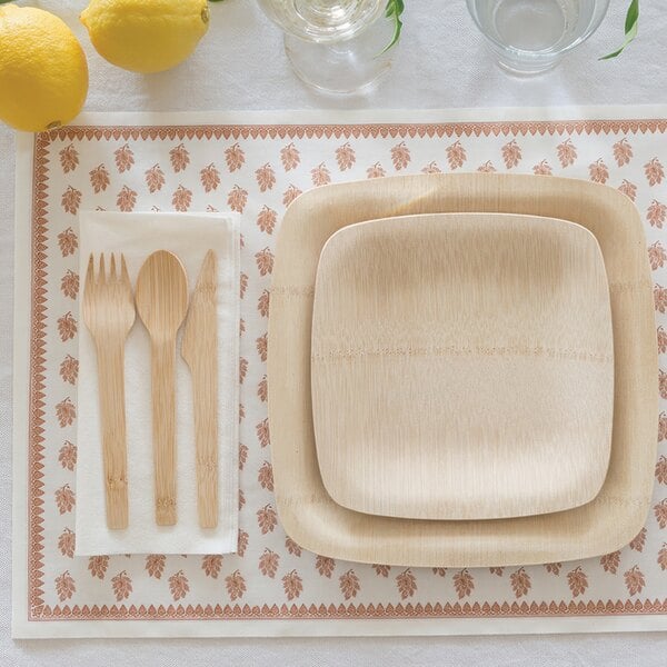 A Bambu Veneerware disposable bamboo knife on a plate with a fork and a lemon.