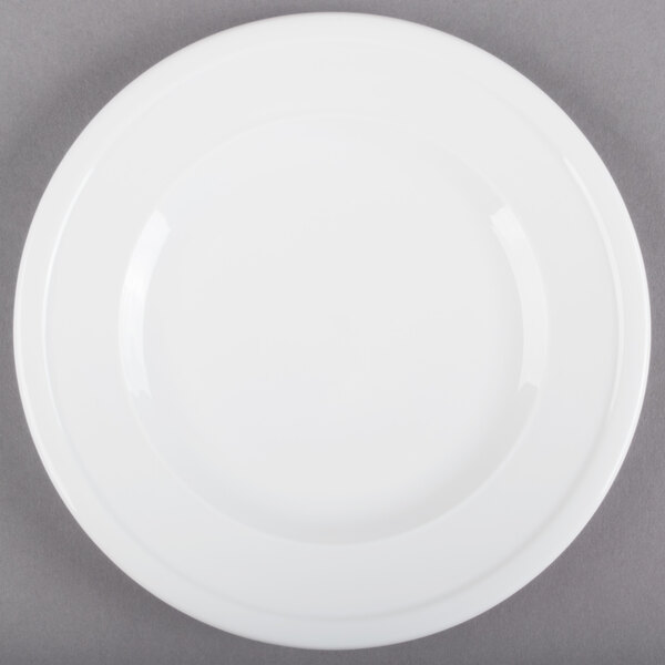 A Libbey alpine white porcelain plate with a rim on a gray surface.