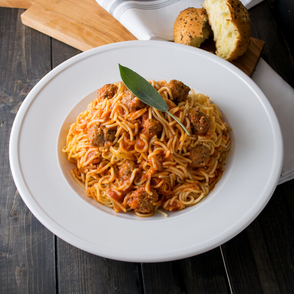 A Libbey alpine white porcelain pasta bowl filled with spaghetti topped with meatballs and a leaf.