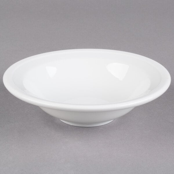 A Libbey Alpine White Porcelain Grapefruit Bowl with a rim on a gray surface.
