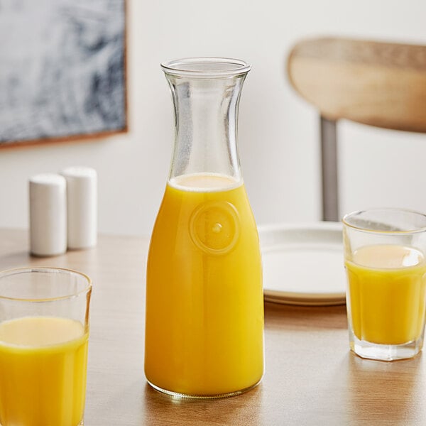 A table with a glass carafe and glasses of orange juice.