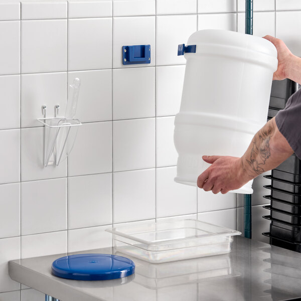 A 5-gallon white polypropylene ice tote kit with a blue lid, 12 oz. scoop, scoop holder, and wall mounting bracket.