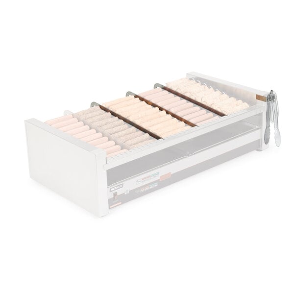 A white Nemco divider kit in a machine with several hot dogs.