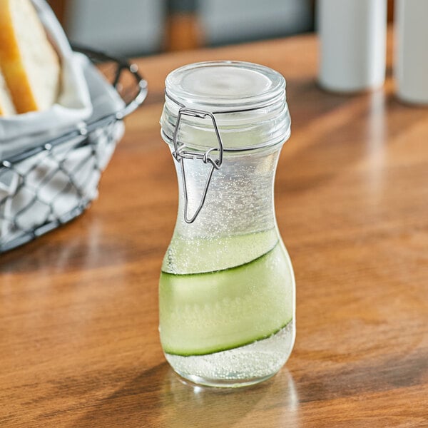 An Acopa glass carafe with cucumber water in it on a table.