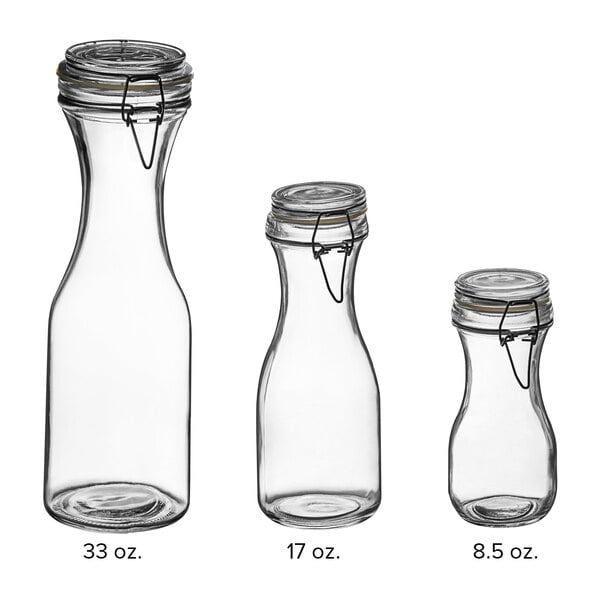A group of Acopa glass carafes with resealable black lids.