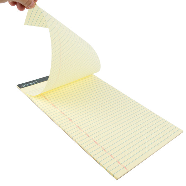 A hand holding a yellow lined Docket writing pad.