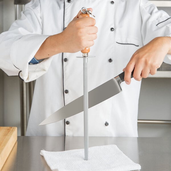 Person in white chef coat sharpening knife with knife sharpener