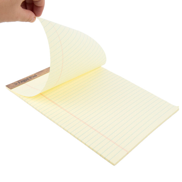 A hand holding a yellow lined TOPS legal pad.