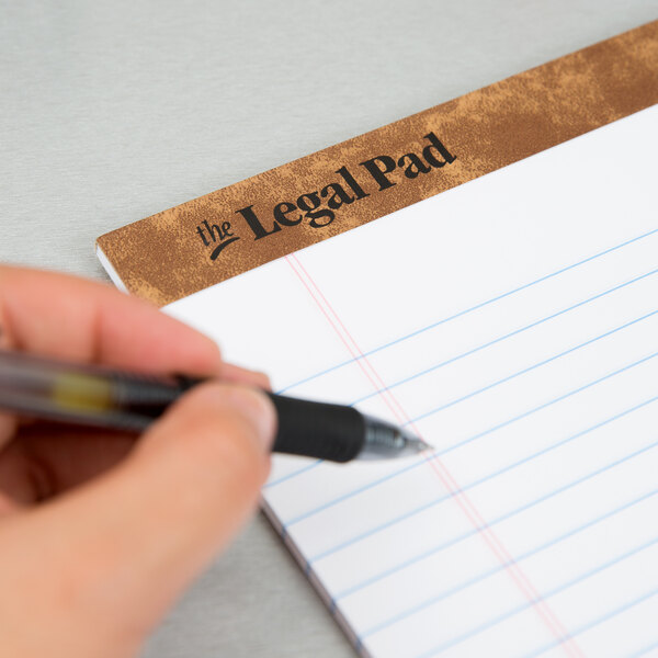 A hand holding a pen over a TOPS legal pad.