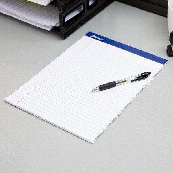 An Ampad wide ruled white writing pad with a pen on it.