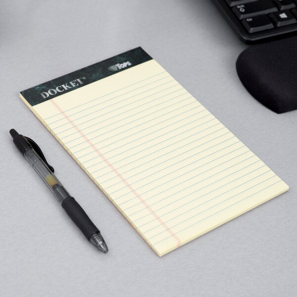 A TOPS Docket narrow ruled notepad and pen on a table.