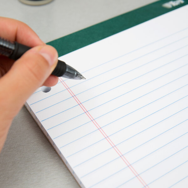 A hand holding a pen over a TOPS notebook filled with lined paper.