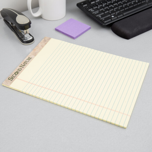 A TOPS Second Nature wide ruled legal pad on a desk with a stapler.