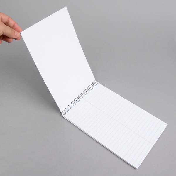 A hand holding a white wirebound Ampad steno pad.
