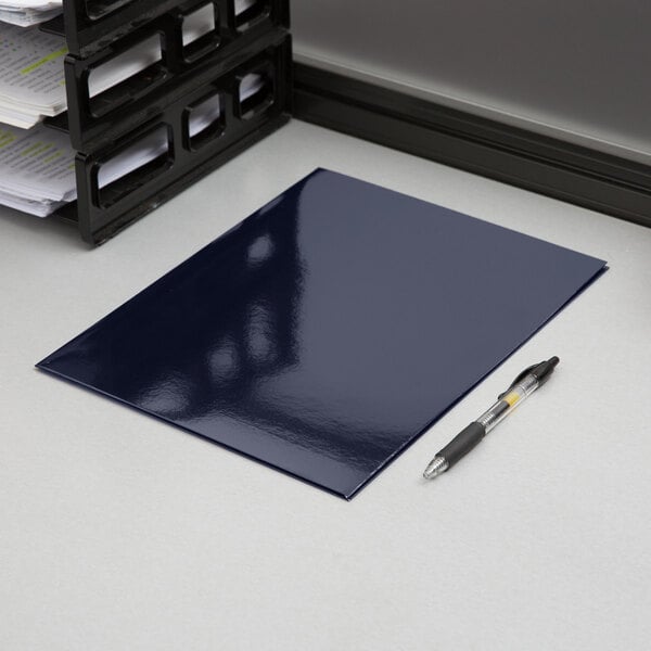 A navy blue Oxford paper pocket folder with a pen on top of it on a white surface.