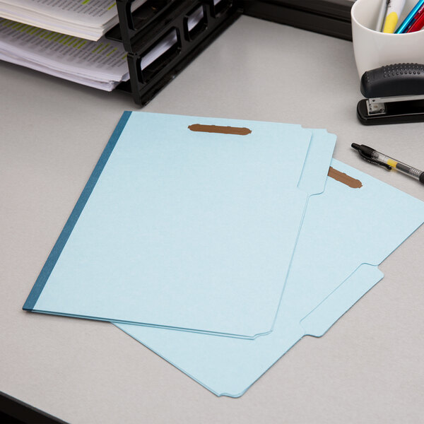 Two blue Pendaflex fastener folders on a desk.