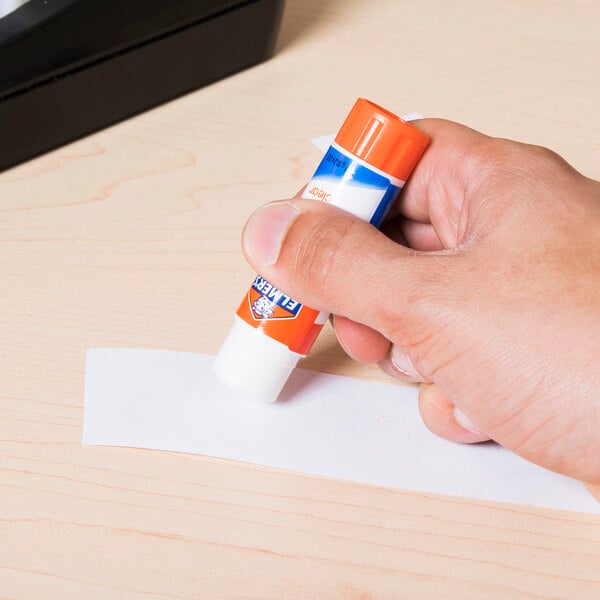 A hand holding an Elmer's clear glue stick.