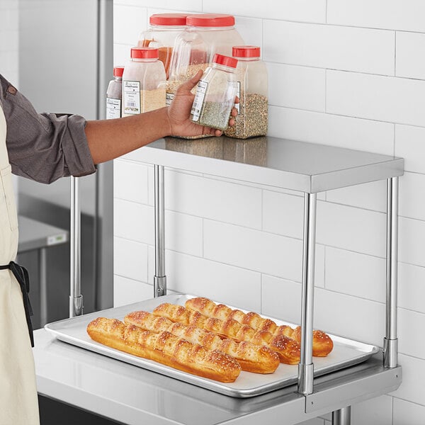 A person holding a Regency stainless steel overshelf with food on a tray.