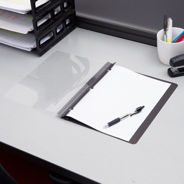 A desk with a clipboard and a stack of papers with a cup of pens on it.