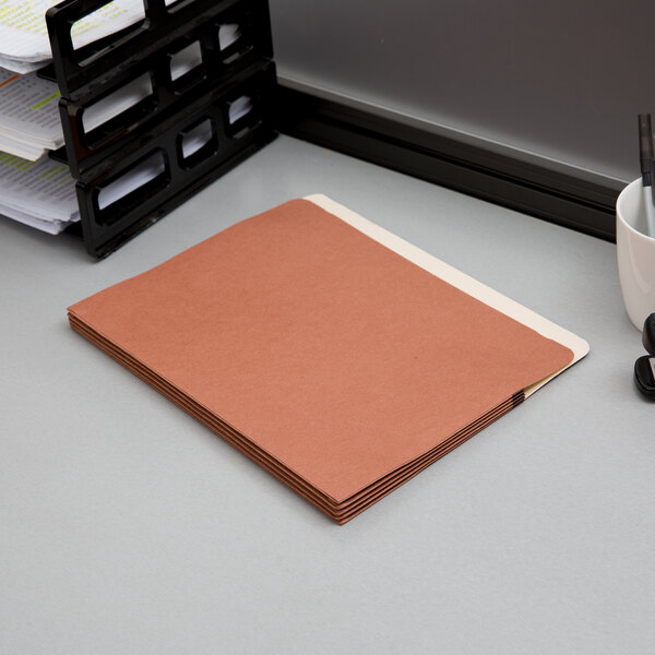 A brown Pendaflex letter size file pocket on a desk.